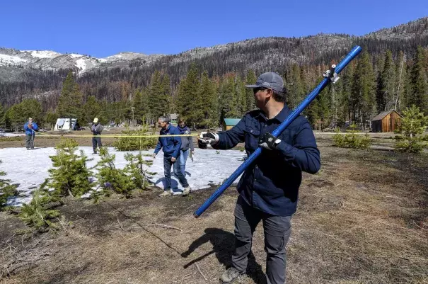 Images shows snow surveyors measuring trace amounts of snow.