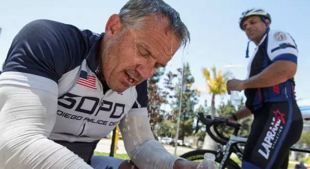 Water from his water bottle drains off cyclist and race coordinator Darrell McPherren, a retired San Diego Police sergeant, as he and Los Angeles Police officer Andy Vergala try to cool off with the temperatures at 102 degrees after competing in the bike race portion of the United States Police and Fire Championships, which going on all this week in San Diego County, in Escondido on Sunday. Photo: Hayne Palmour IV / San Diego Union-Tribune