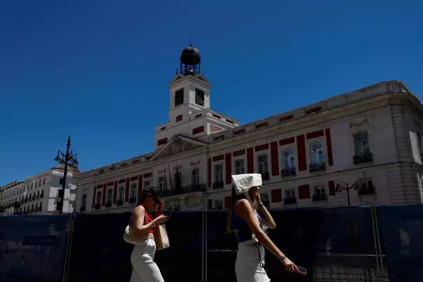 A woman covers her head with a bag as she walks at Puerta del Sol square during a hot day as Spain braces for a heatwave in Madrid, Spain, June 10, 2022. (Credit: REUTERS/Susana Vera/File Photo)