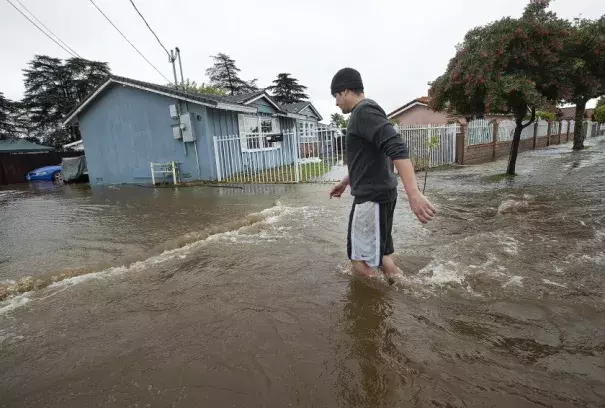 Alberto Rodriguez walks through a flooded street outside his Mission Hills home in December 2019.(Los Angeles Times)
