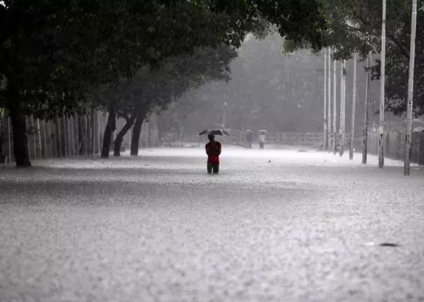 An Indian man shelters under an umbrella as he walks through floodwaters in Chennai on December 1, 2015, during a downpour of heavy rain in the southern Indian city. Photo by STRDEL/AFP/Getty Images