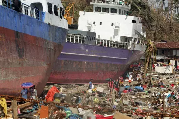 Filipinos walk past ships washed ashore in the devastated city of Tacloban. Photo: Francis R. Malasig, European Pressphoto Agency