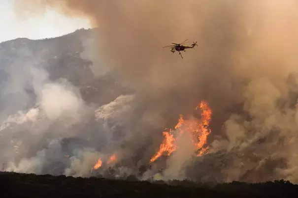 A helicopter drops water on the wildfire in California. Photo: FEMA