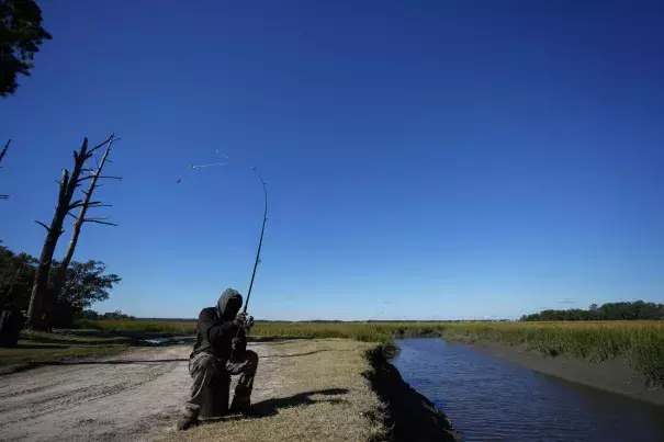 Gullah Geechee fisherman Ricky Wright casts his line as he fishes for bass in a marsh waterway with eroded banks on St. Helena Island, S.C., Sunday, Oct. 31, 2021. (AP Photo/Rebecca Blackwell)