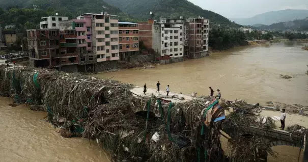 Residents gingerly walking over a bridge mounded with debris in Bandong Town in China’s Fujian province. Photo: STR / AFP / Getty Images