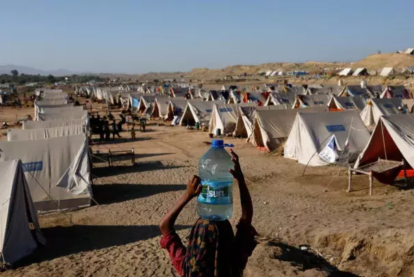 A displaced girl carries a bottle of water she filled from nearby stranded flood-waters, as her family takes refuge in a camp, in Sehwan, Pakistan, September 30, 2022. REUTERS/Akhtar Soomro TPX IMAGES OF THE DAY