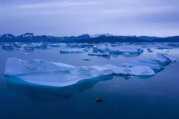FILE - A boat navigates at night next to large icebergs near the town of Kulusuk, in eastern Greenland on Aug. 15, 2019. A sharp spike in Greenland temperatures since 1995 showed the giant northern island 2.7 degrees (1.5 degrees Celsius) hotter than its 20th-century average, the warmest in more than 1,000 years, according to new ice core data. (Credit: AP Photo/Felipe Dana, File)