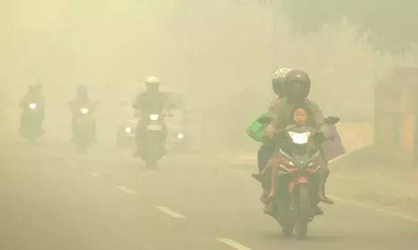 Motorists ride on a road as thick haze from forest fires shrouds the city in Palangkaraya, Central Borneo, Indonesia, on Tuesday, October 27, 2015. The haze has blanketed parts of western Indonesia for about two months and affected neighboring countries like Singapore, Malaysia and Thailand. Image credit: Associated Press.
