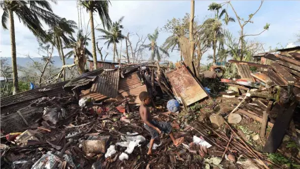 In Vanuatu's capital, Port Vila, a boy named Samuel kicked a ball through the ruins of his family's home as his father, Phillip, at back, picked through the debris on Monday. Image: Dave Hunt, AP