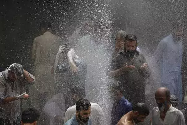 People are seen bathing while others cool off from the heat as they are sprayed with water jetting out from a leaking water pipeline in Karachi, Pakistan, June 25, 2015 during a heat wave. Photo: Akhtar Soomros, Reuters