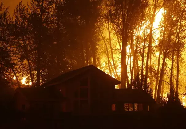 A wildfire burns behind a home in Twisp, Washington, in August. Authorities urged people in the town to evacuate because of the fast-moving blaze. (Ted S. Warren/AP)