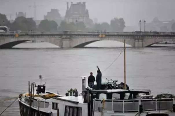 A man waves to somebody on a barge on the Seine river during floods, in Paris, Sunday, June 5, 2016. The riverside Grand Palais exhibition hall in Paris reopened Sunday as floodwaters slowly receded from the French capital, though risks remain for other regions. Photo: Thibault Camus, AP