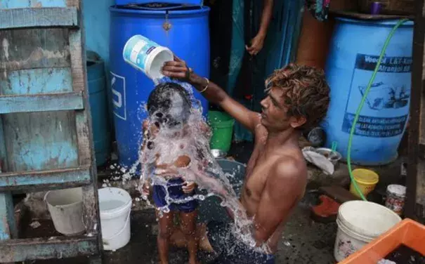 In this May 23, 2016 file photo, a man bathes his son on a hot afternoon in Mumbai, India. Federal scientists say Earth sizzled to its 13th straight month of record heat in May. Photo: Rafiq Maqbool, AP