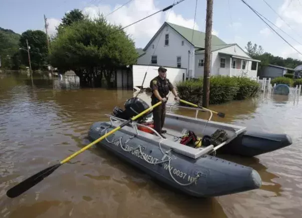 Lt. Dennis Feazell, of the West Virginia Department of Natural Resources, rows his boat as he and a co-worker search flooded homes in Rainelle, W. Va. on June 25, 2016. About 32,000 West Virginia homes and businesses remain without power Saturday after severe flooding hit the state. The West Virginia Division of Homeland Security and Emergency Management also said that more than 60 secondary roads in the state were closed. Photo: Steve Helber, AP