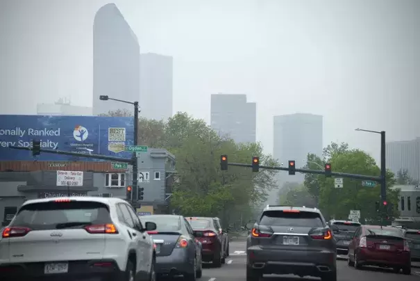 Motorists wait for a red light on westbound 18th Avenue at Park Avenue as smoke shrouds the skyline Friday, May 19, 2023, in downtown Denver. Smoke from numerous fires in the Canadian province of Alberta has rolled into Colorado Friday, giving Denver a ranking of third worst air quality of all major cities globally. The Colorado Department of Public Health and Education has issued an air quality health advisory alert as a result of the inflow of smoke across the Centennial State. (Credit: AP Photo/David Zal