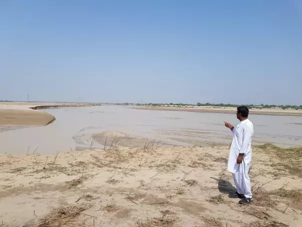 Omar Daraz, a cotton grower, points to the flood water that destroyed his crop in Hasanabad, Pakistan, September 28, 2022. Thomson (Credit: Reuters Foundation/Waqar Mustafa)
