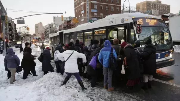 Commuters trudge through piles of snow boarding a bus in Manhattan. Photo: AP