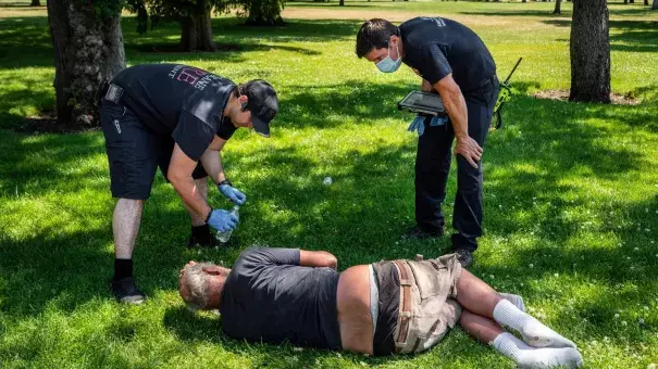 About a year ago, a heatwave swept through the Pacific Northwest and killed more than 100 people. In the photo above, first responders in Spokane, WA performed a welfare check on a man in a public park during that 2021 heatwave. (Credit: Colin Mulvany / COEUR D’ALENE PRESS / AP)