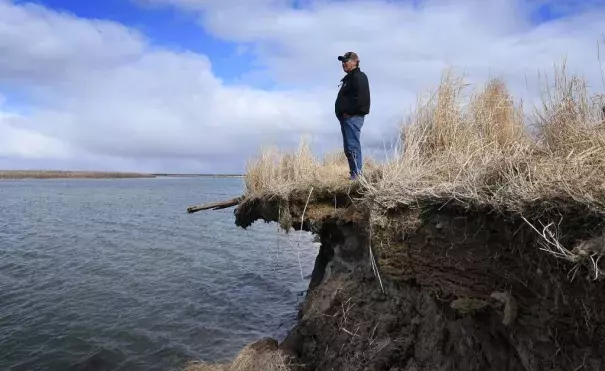 Tribal elder Warren Jones stands on a site threatened by climate change erosion caused by melting permafrost tundra and the disappearance of sea ice which formed a protective barrier, at the Yupik Eskimo village of Quinhagak on the Yukon Delta in Alaska on April 13, 2019. Credit: Mark Ralston, AFP, Getty Images