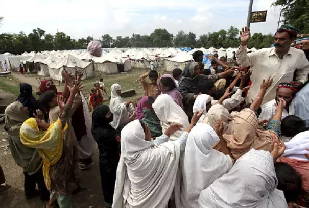 Flood-affected crowds get relief food at a camp in Nowshera, northwest Pakistan, on Monday. The number of people suffering from the disaster now exceeds 13 million. Photo: Sajjad, AP