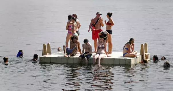 A lifeguard, center in red, overseas a platform as people beat the oppressive heat and humidity Thursday, July 21, 2016, at Lake Harriet in Minneapolis. Photo: Jim Mone, AP