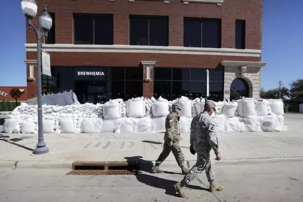 Iowa National Guard members walk past a local business covered in sandbags, Monday, Sept. 26, 2016, in Cedar Rapids, Iowa. Residents are waiting anxiously as a quickly rising Cedar River threatens to inundate their city with devastating floodwaters for the second time in eight years. Photo: Charlie Neibergall, AP