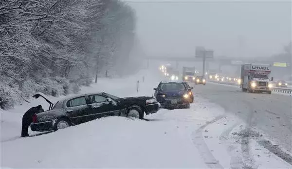 As traffic creeps past on the New Jersey Turnpike, drivers work on cars stuck in the snow Saturday, Jan. 7, 2017, near New Brunswick, N.J. Photo: Mel Evans, AP