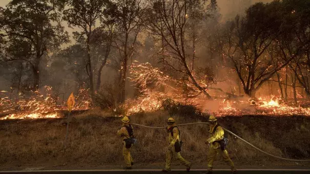 Firefighters try to keep a wildfire from jumping a street near Oroville, Calif., on Saturday. Evening winds drove the fire through several neighborhoods, leveling homes in its path. Photo: Noah Berger, AP