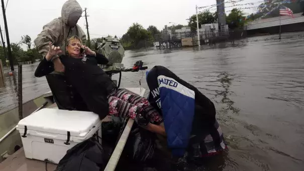 Rhonda Worthington is lifted into a boat while on her cellphone with a 911 dispatcher on Monday in Houston. Houston and other areas along the Gulf Coast are facing intense flooding from Tropical Storm Harvey. Photo: LM Otero, AP