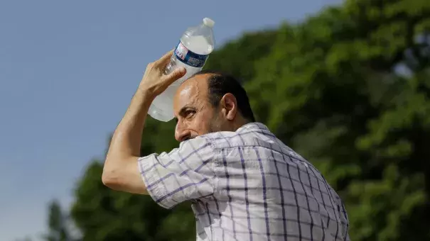 A man uses a cool bottle of water to cool off in the Trocadero gardens in Paris, Friday, June 28, 2019. Credit: Lewis Joly, AP