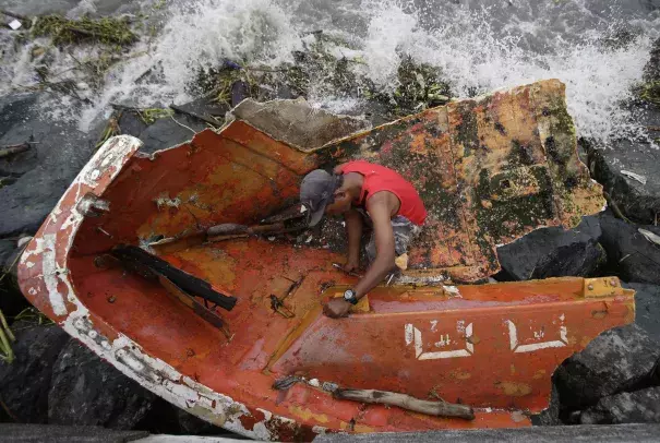 Filipino Joybin Marayo, 58, salvages metals on a damaged boat that was washed ashore by strong waves brought about by Typhoon Haima in Manila, Philippines on Thursday Oct. 20, 2016. Photo: Aaron Favila