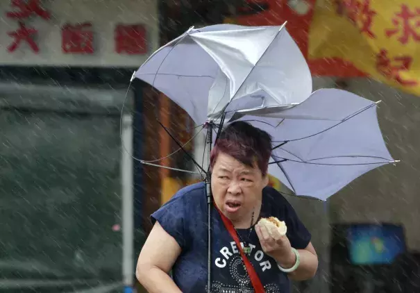 A woman eats and struggles with her umbrella against powerful gusts of wind generated by typhoon Megi across the the island in Taipei, Taiwan, Tuesday, Sept. 27, 2016. Schools and offices have been closed on Taiwan and people in dangerous areas have been evacuated as a large typhoon with 162 kilometers- (100 miles-) per-hour winds approaches the island. Photo: Chiang Ying-ying, Associated Press
