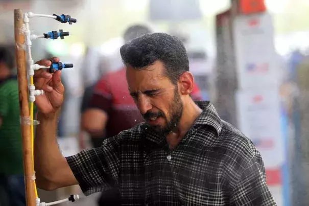 An Iraqi man using an atomizer made available for people outside a shop selling cooling and ventilation products on July 20, the first day of a two-day holiday for government employees Iraqi authorities announced due to the heat. Photo: Ahmad Al-Rubay, Agence France-Presse
