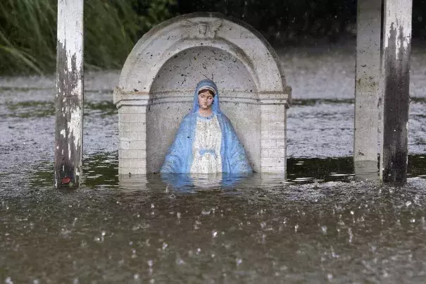 A statue of the Virgin Mary is seen partially submerged in flood water as it rains in Sorrento, La., Saturday. Photo: Reuters