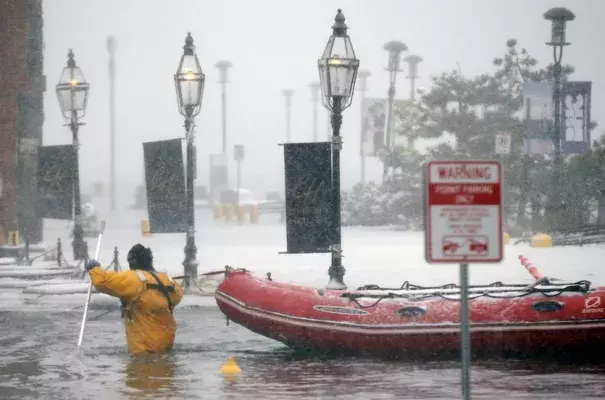 A Boston firefighter wades through flood waters from Boston Harbor on Long Wharf on Thursday, Jan. 4, 2018, after Winter Storm Grayson’s storm surge brought the highest coastal water levels ever recorded in Boston. Photo: Michael Dwyer, AP