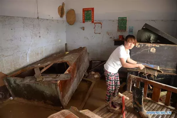 A villager clears the debris at her home in Nanshitun village of Xingtai City, north China's Hebei Province, July 24, 2016. Torrential rain and floods have left 34 people dead and 13 people missing in Xingtai City by Sunday as well as some 9,200 homes were still without electricity. Photo: Xinhua