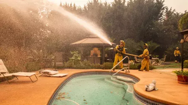 Firefighters spray water on a spot fire at a home during the Kincade Fire on Vinecrest Road in Windsor, Calif., on Sunday, Oct. 27, 2019. Credit: The Weather Channel