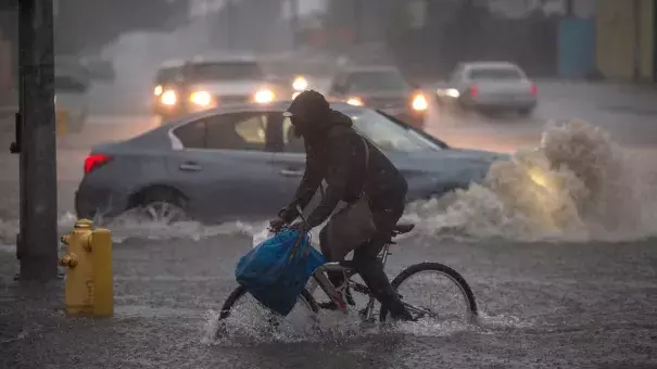 A bicyclist in Sun Valley rides along a flooded street as powerful atmospheric river storms move across California. Photo: David McNew, Getty Images