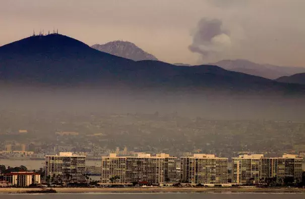 Smoke rises from a wildfire near Coronado, Calif. Researchers are linking climate change to rising levels of air pollution from wildfires. (AP Photo/Denis Poroy)