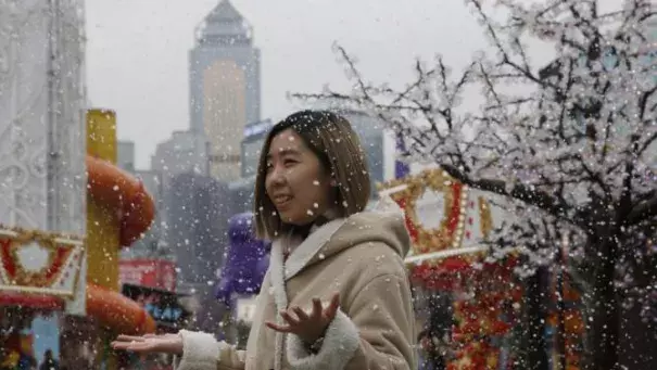 A visitor enjoys the artificial snow made of foam at a carnival in Hong Kong, on Jan. 26, 2016. In Hong Kong, the mercury dipped to its lowest in six decades. Photo: Kin Cheung, AP