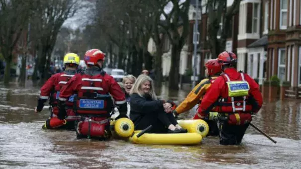 Emergency workers use an inflatable raft to rescue two women from flooding. Photo: BBC
