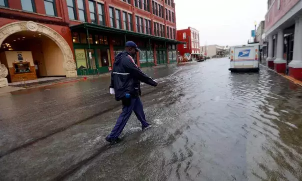 A postman walks through flooded streets in Galveston, Texas from Tropical Depression Imelda on Sept. 18, 2019. Photo: David J. Phillip, AP