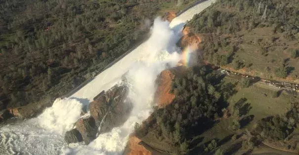 Water pours over the damaged main spillway at the Oroville Dam and over a hillside. Photo: California Department of Water Resources