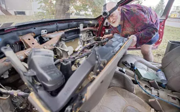 Arthur Knight works on his Lexus, which was damaged in the flooding outside of this home on Railroad Street in Milesburg. Photo: Abby Drey