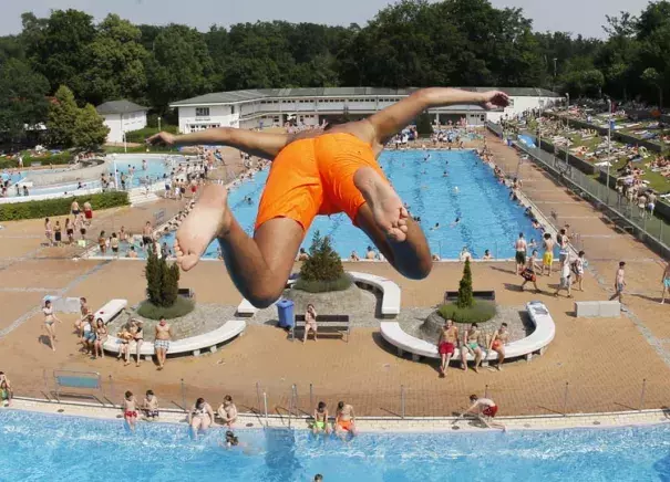 A young boy jumps from a 7.5 meter platform at a crowded outdoor pool during a record heat wave in Frankfurt, Germany, Friday, July 3, 2015. Photo: Michael Probst, AP