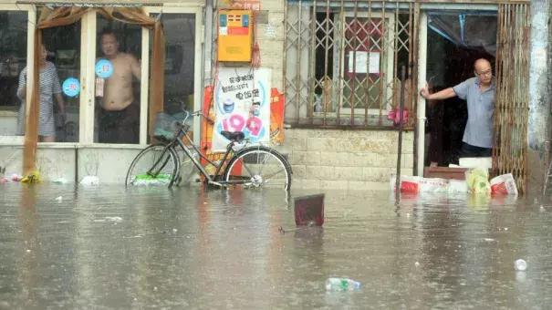 Chinese residents look at a flooded area caused by heavy rain in Beijing on July 20, 2016. Photo: STR/AFP/Getty Images