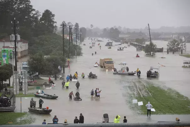 People walk down a flooded street as they evacuate their homes after the area was inundated with flooding from Hurricane Harvey on August 28, 2017 in Houston, Texas. Photo: Joe Raedle, Getty Images
