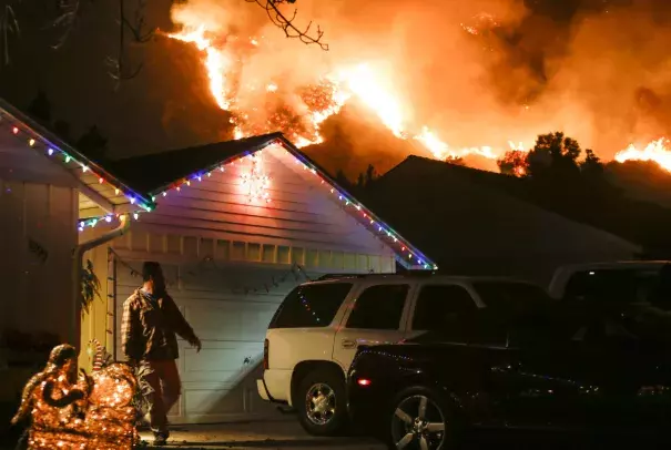 A man prepares to evacuate his home as a wildfire burns along a hillside near homes in Santa Paula, California. Photo: Ringo Chiu, AFP/Getty Images