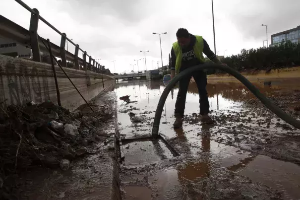 A worker tries to clean a sewer as water covers an interchange of a highway in Elefsina, western Athens, on Wednesday, Nov. 15, 2017. Flash floods in the Greek capital’s western outskirts Wednesday converted roads into raging torrents of mud and debris, killing at least five people and inundating homes and businesses. Photo: Petros Giannakouris/Associated Press