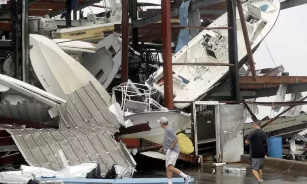 People walk past a boat storage facility that was damaged by Hurricane Harvey, Saturday, Aug. 26, 2017, in Rockport, Texas. Photo: Eric Gay, AP